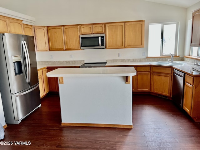 kitchen featuring a kitchen island, vaulted ceiling, stainless steel appliances, light countertops, and a sink