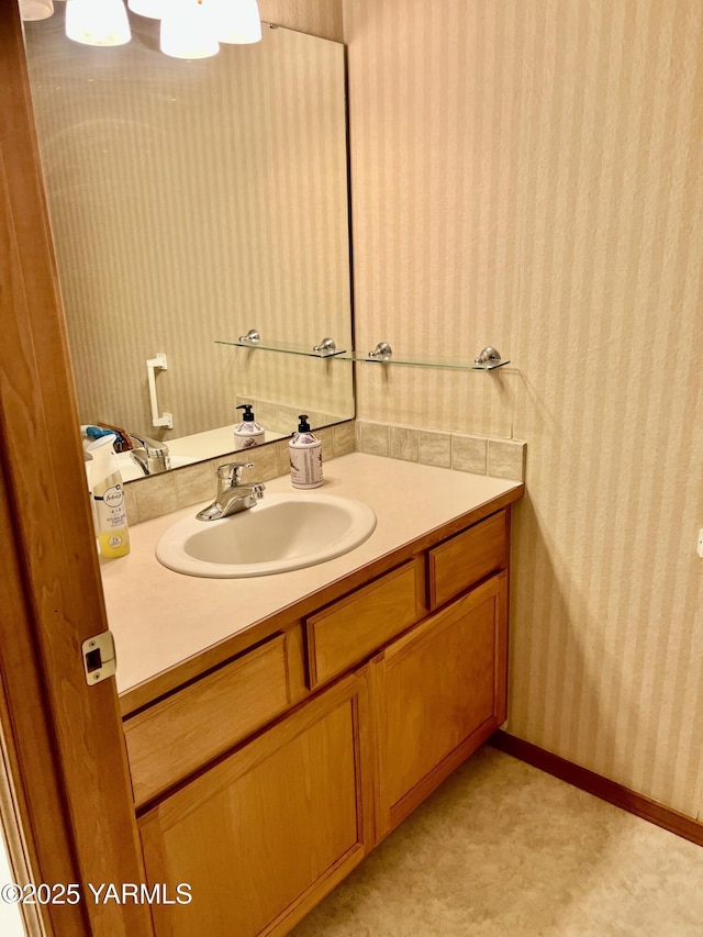 bathroom with wallpapered walls, baseboards, and vanity