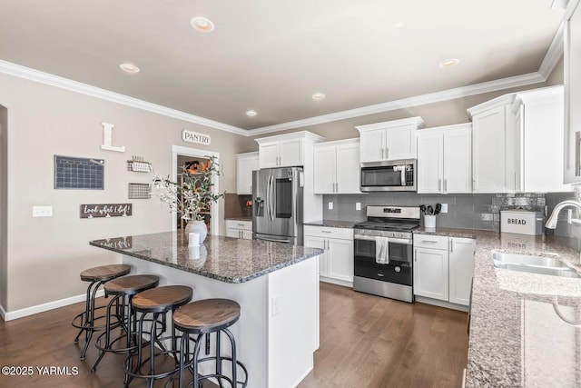 1589 Valhalla Loop, Selah, WA 98942 - kitchen with appliances with stainless steel finishes, a sink, a kitchen island, ornamental molding, and dark stone counters