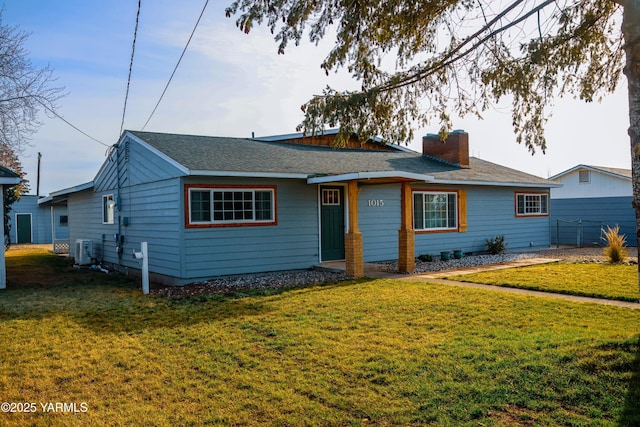 ranch-style home with a shingled roof, a chimney, central AC unit, and a front yard