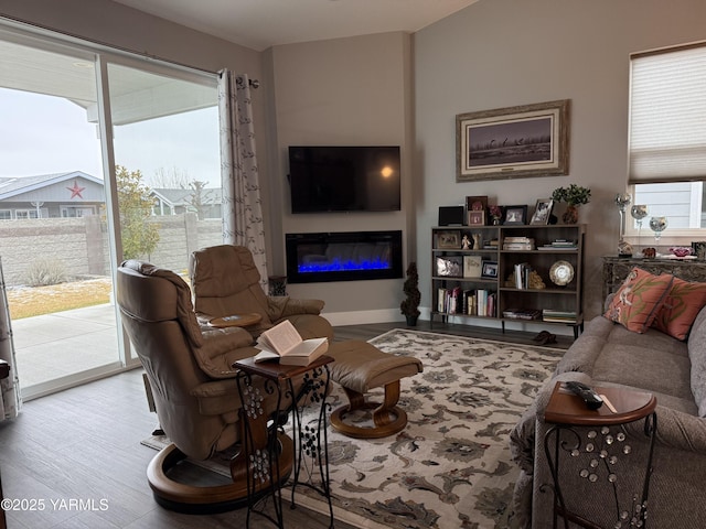 living room with light wood-type flooring, a glass covered fireplace, and baseboards