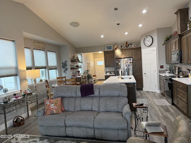 living room featuring lofted ceiling, baseboards, wood finished floors, and recessed lighting