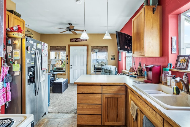 kitchen featuring pendant lighting, a sink, stainless steel fridge, a peninsula, and light countertops