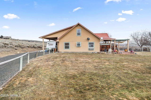 rear view of property with a yard, metal roof, a standing seam roof, and fence