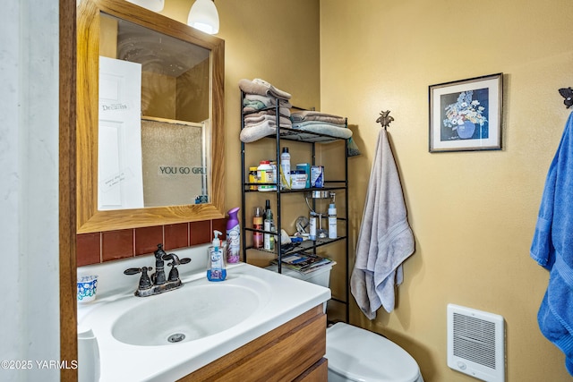 bathroom with heating unit, toilet, a stall shower, and vanity