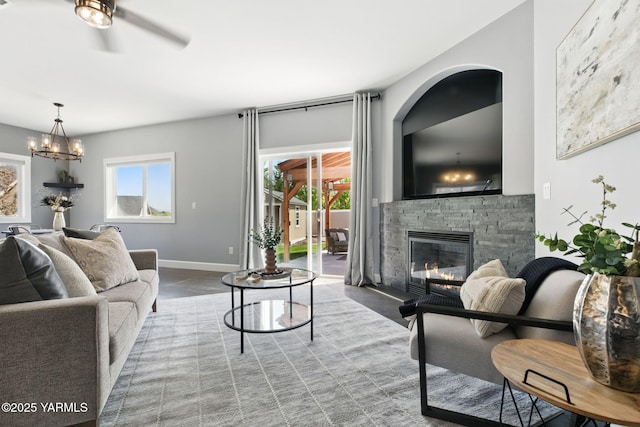 living room with baseboards, a fireplace, ceiling fan with notable chandelier, and wood finished floors