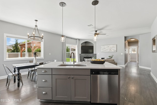 kitchen with a healthy amount of sunlight, dishwasher, a sink, gray cabinetry, and ceiling fan with notable chandelier