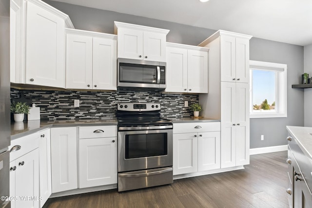 kitchen with baseboards, appliances with stainless steel finishes, white cabinets, and tasteful backsplash