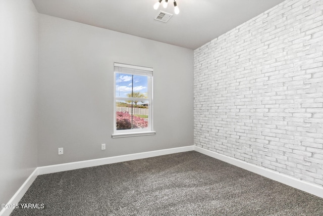 spare room featuring dark carpet, brick wall, and visible vents