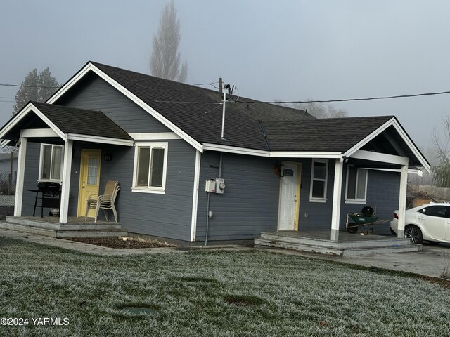 ranch-style house with a porch, a front lawn, and a shingled roof