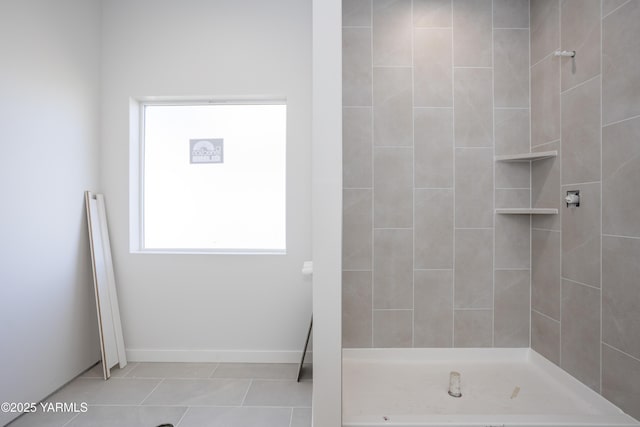 full bath featuring baseboards, a tile shower, and tile patterned floors