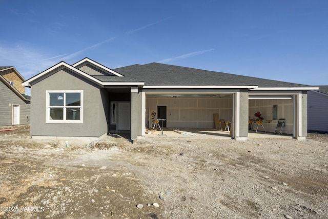 view of front facade featuring roof with shingles, an attached garage, and stucco siding