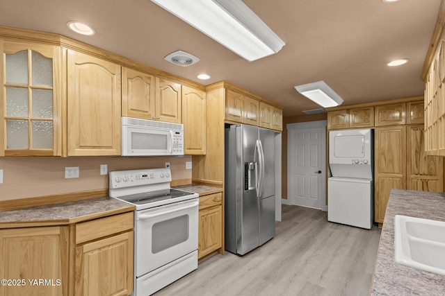 5804 W Walnut St, Yakima, WA 98908 - kitchen with white appliances, stacked washing machine and dryer, glass insert cabinets, light brown cabinetry, and light wood-type flooring