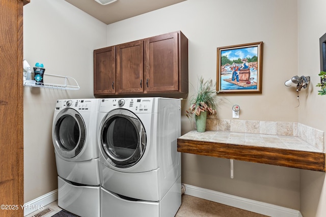 clothes washing area with baseboards, cabinet space, visible vents, and washing machine and clothes dryer