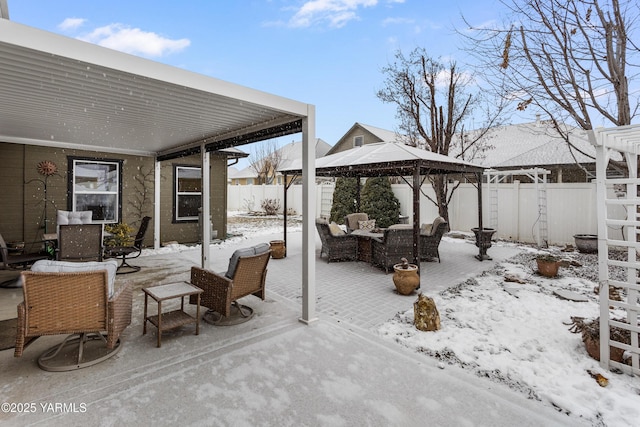 snow covered patio with a fenced backyard, an outdoor living space, and a gazebo