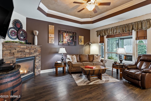 living room with baseboards, a tray ceiling, and dark wood-type flooring