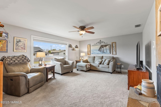 living room featuring carpet flooring, a ceiling fan, visible vents, and baseboards