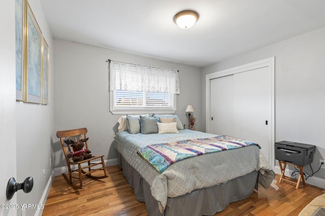 bedroom featuring baseboards, light wood-type flooring, and a closet