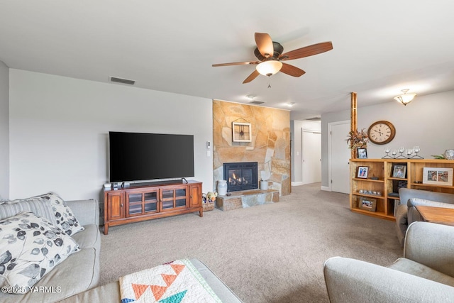 carpeted living room with visible vents, a fireplace, and a ceiling fan