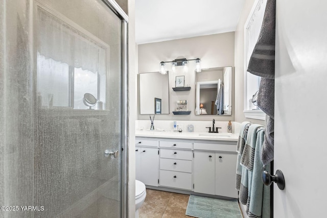 bathroom with double vanity, a stall shower, a sink, tile patterned flooring, and toilet