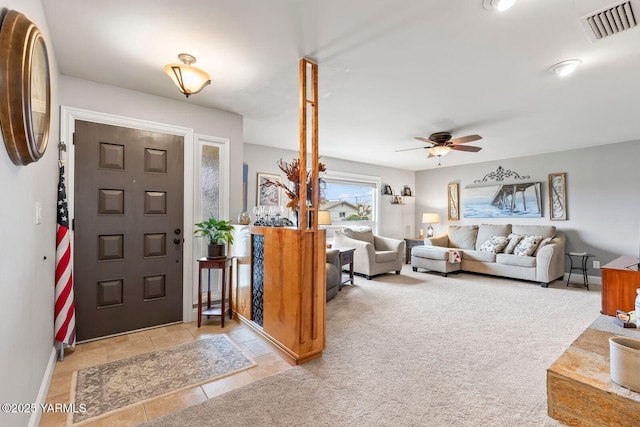 foyer featuring a ceiling fan, visible vents, and light carpet