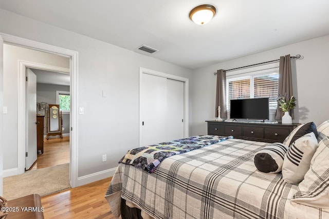 bedroom featuring a closet, visible vents, light wood-style flooring, and baseboards