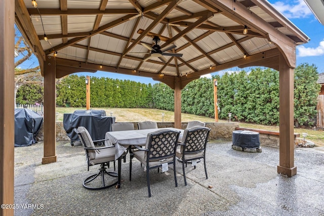 view of patio featuring outdoor dining space, fence, a gazebo, grilling area, and ceiling fan