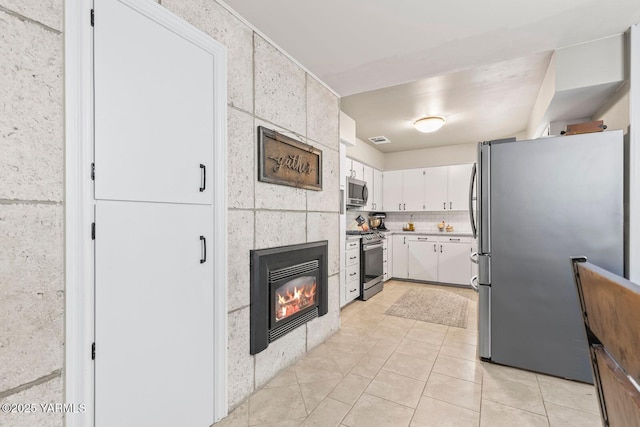 kitchen with visible vents, a tile fireplace, light countertops, white cabinets, and appliances with stainless steel finishes