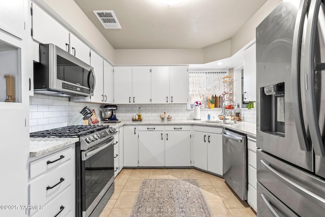 kitchen featuring visible vents, a sink, tasteful backsplash, stainless steel appliances, and white cabinets