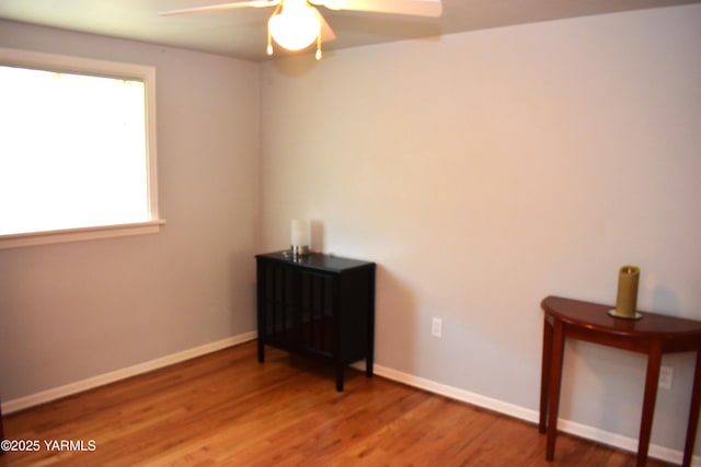 interior space with baseboards, ceiling fan, and wood finished floors