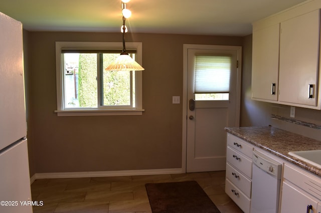 kitchen featuring baseboards, white cabinets, light stone countertops, and white appliances