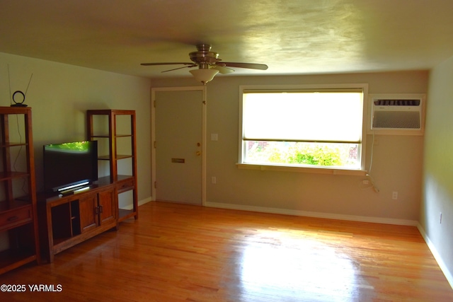 unfurnished living room featuring baseboards, ceiling fan, light wood-type flooring, and a wall mounted air conditioner