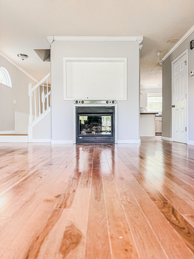 unfurnished living room with wood-type flooring and crown molding