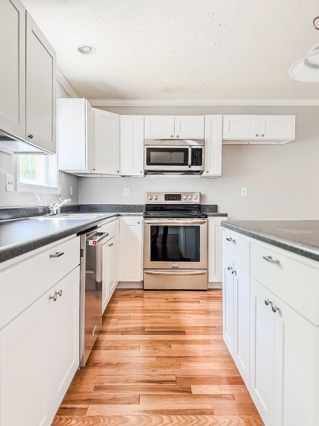 kitchen featuring stainless steel appliances, light hardwood / wood-style floors, and white cabinetry