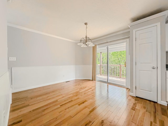 unfurnished room featuring ornamental molding, light hardwood / wood-style floors, and a notable chandelier