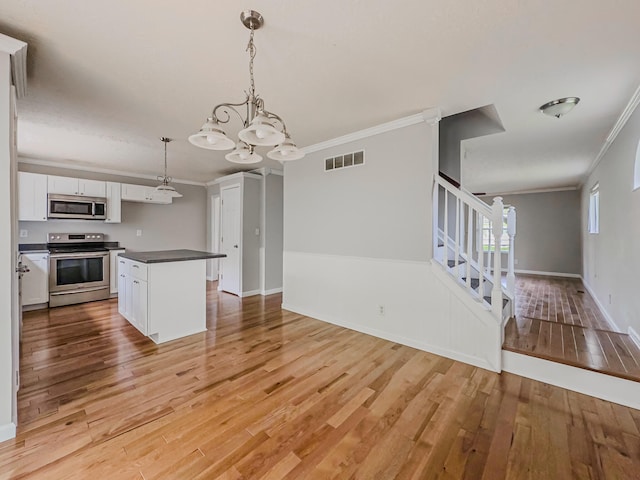 kitchen with appliances with stainless steel finishes, hanging light fixtures, light hardwood / wood-style floors, white cabinets, and a notable chandelier