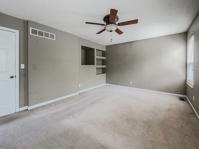 carpeted spare room featuring a textured ceiling and ceiling fan