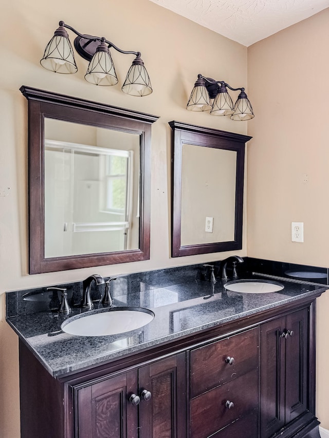 bathroom featuring dual bowl vanity and a textured ceiling