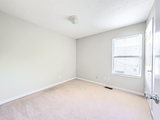 carpeted empty room featuring a textured ceiling