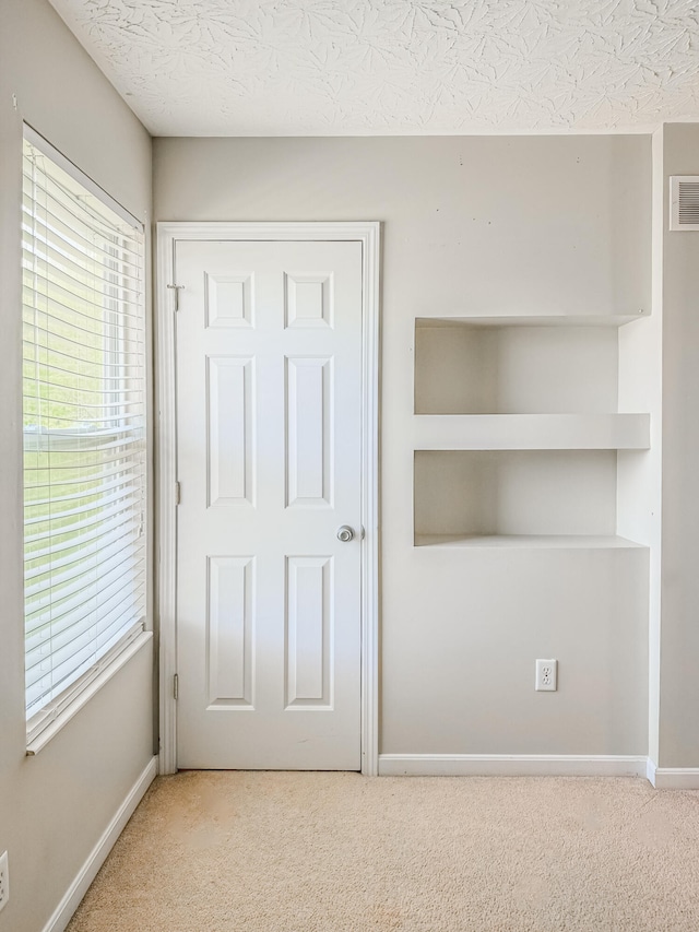 interior space with light colored carpet and a textured ceiling