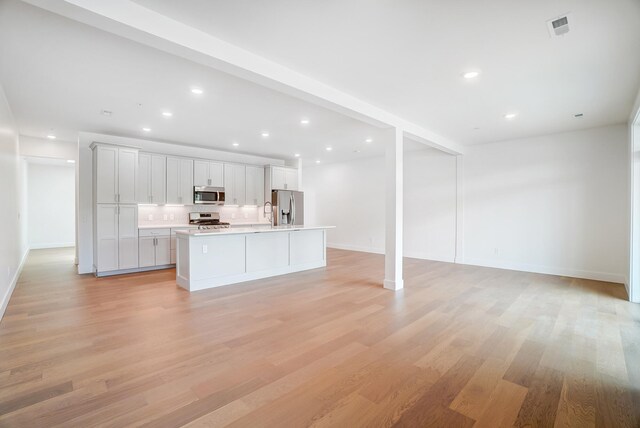 kitchen with a center island with sink, light wood-type flooring, appliances with stainless steel finishes, and white cabinetry