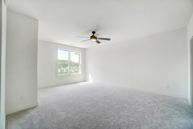 empty room featuring ceiling fan and light colored carpet