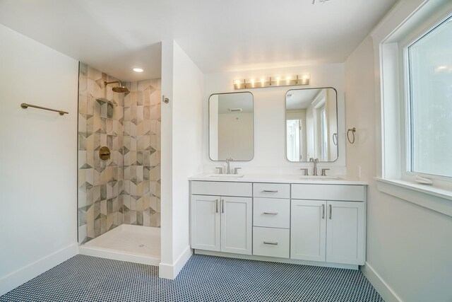 bathroom featuring dual vanity, tiled shower, and plenty of natural light