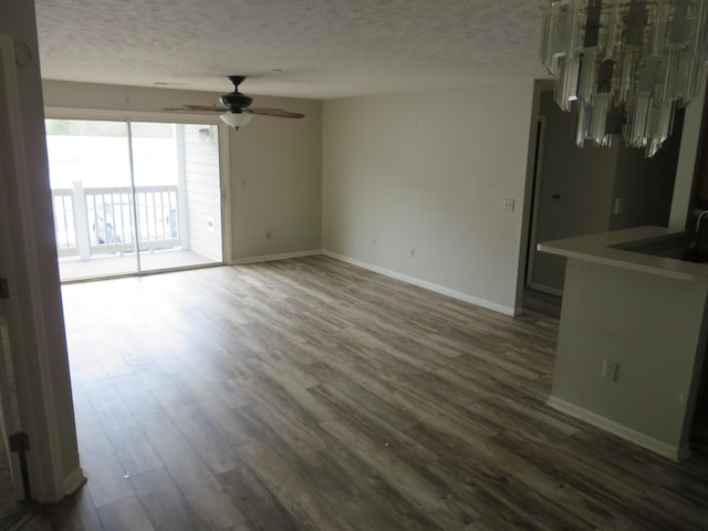 unfurnished living room with baseboards, dark wood finished floors, and a textured ceiling