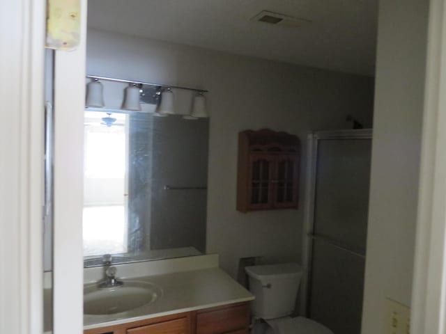 bathroom featuring visible vents, toilet, vanity, and a shower stall