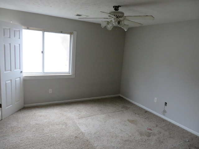 spare room with visible vents, carpet, a ceiling fan, and baseboards