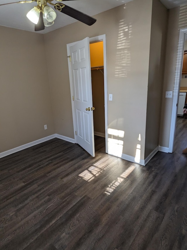 unfurnished bedroom featuring dark hardwood / wood-style flooring, ceiling fan, a walk in closet, and a closet