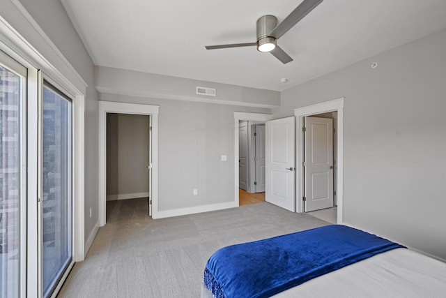 carpeted bedroom with ceiling fan and a walk in closet