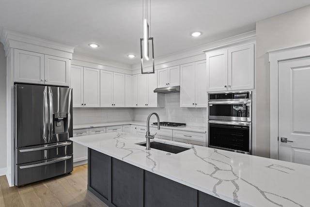 kitchen with decorative light fixtures, white cabinets, light stone countertops, and stainless steel appliances