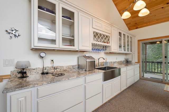 kitchen featuring sink, wooden ceiling, vaulted ceiling, light carpet, and white cabinets